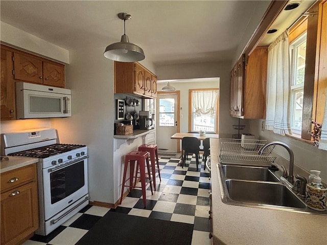 4019 Holly St, Kansas City, MO 64111 - kitchen featuring white appliances, tile patterned floors, brown cabinets, and pendant lighting