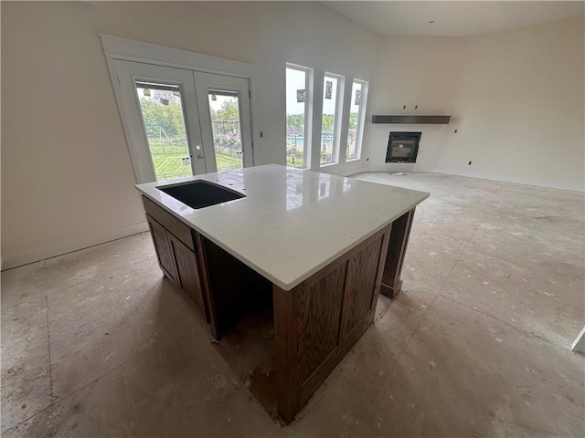 2211 Prairie Creek Dr, Kearney, MO 64060 - kitchen featuring french doors, a glass covered fireplace, a kitchen island, dark brown cabinets, and light countertops
