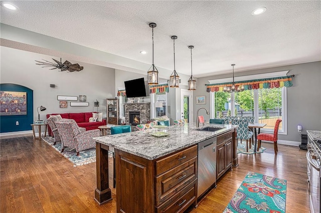 5320 N 101st Ter, Kansas City, KS 66109 - kitchen featuring a sink, dishwasher, a stone fireplace, dark wood-style flooring, and a textured ceiling