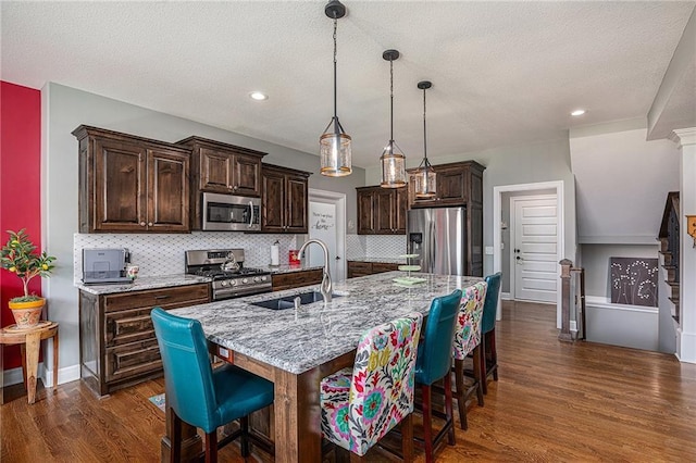 5320 N 101st Ter, Kansas City, KS 66109 - kitchen featuring appliances with stainless steel finishes, a sink, a kitchen breakfast bar, dark brown cabinetry, and dark wood-type flooring
