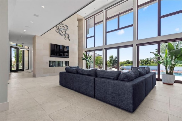 10712 W 165th St, Overland Park, KS 66221 - tiled living area with a towering ceiling, plenty of natural light, a glass covered fireplace, recessed lighting, and french doors
