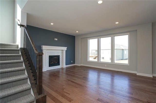 18256 W 166th St, Olathe, KS 66062 - unfurnished living room featuring dark wood-style floors, a fireplace, stairway, and recessed lighting