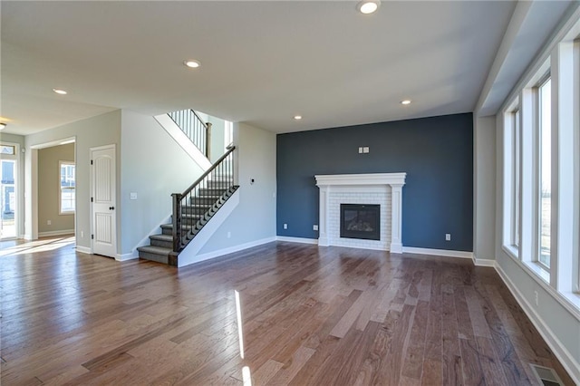 18256 W 166th St, Olathe, KS 66062 - unfurnished living room with healthy amount of natural light, dark wood finished floors, a brick fireplace, stairway, and recessed lighting