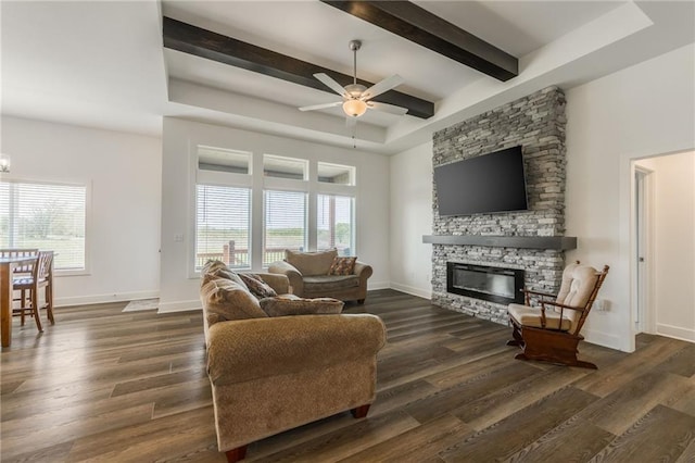 living room featuring beam ceiling, a fireplace, baseboards, ceiling fan, and dark wood-style floors