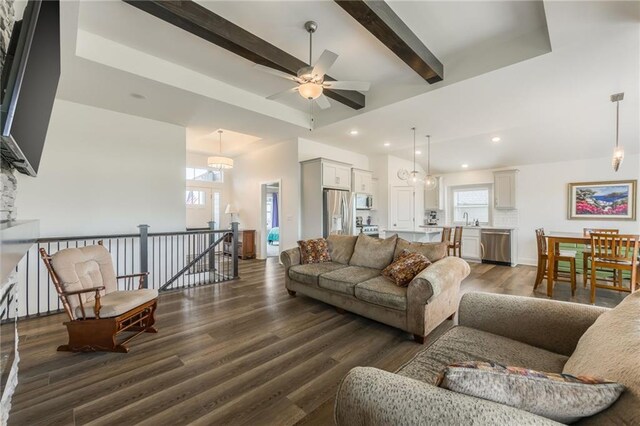 living area with dark wood-type flooring, ceiling fan, beam ceiling, and a healthy amount of sunlight