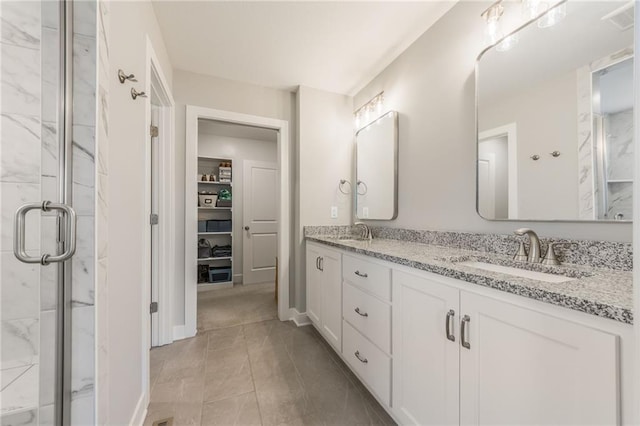 full bathroom featuring double vanity, a spacious closet, a shower stall, and a sink