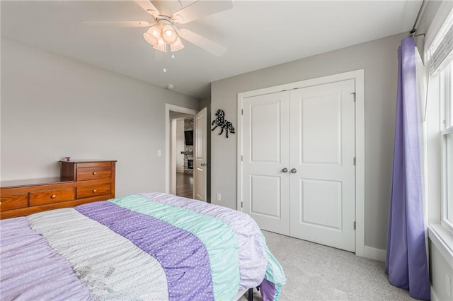 bedroom with ceiling fan, light colored carpet, and a closet