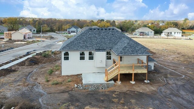 back of house with a deck, cooling unit, and a shingled roof