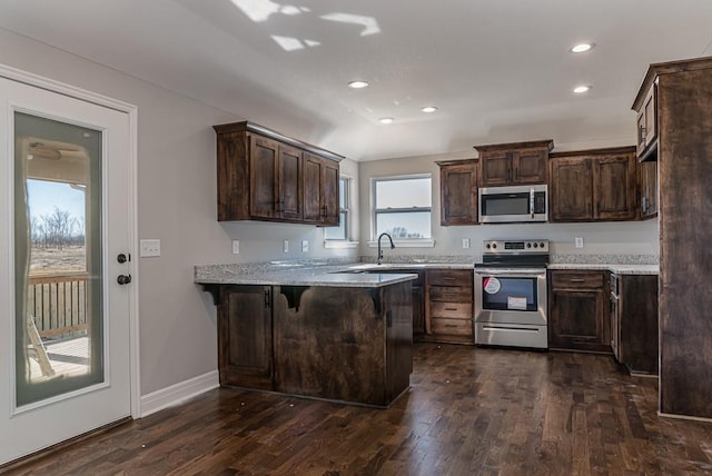 kitchen featuring a peninsula, dark wood finished floors, dark brown cabinetry, and stainless steel appliances