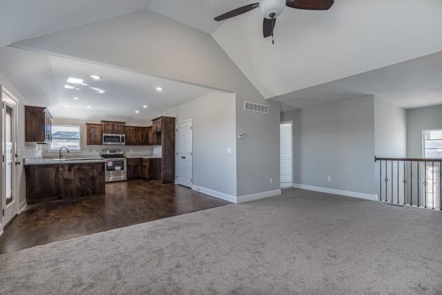 unfurnished living room with a sink, ceiling fan, baseboards, dark colored carpet, and visible vents