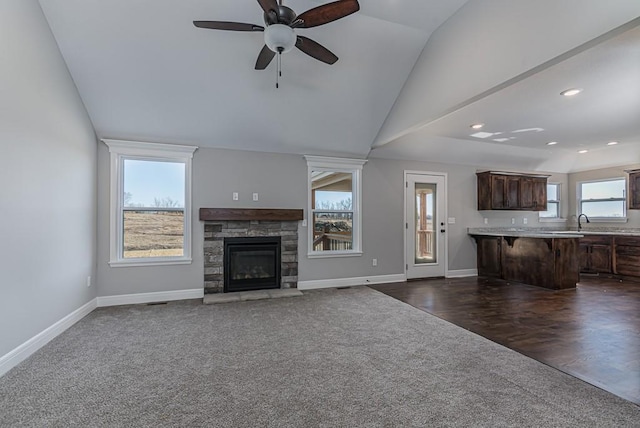 unfurnished living room with dark colored carpet, baseboards, lofted ceiling, ceiling fan, and a fireplace