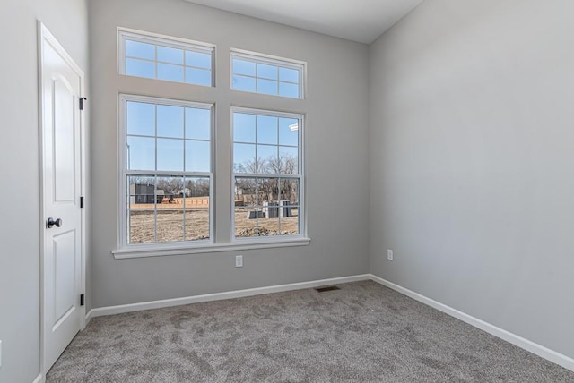 unfurnished room with baseboards, visible vents, and carpet