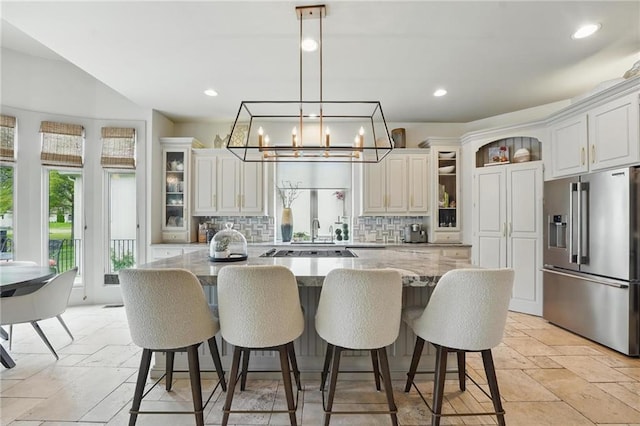 kitchen featuring stone tile floors, backsplash, a kitchen island, and stainless steel fridge with ice dispenser