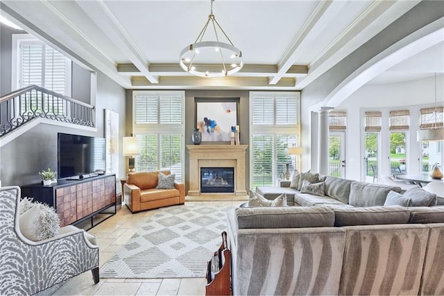 living area with decorative columns, crown molding, arched walkways, beamed ceiling, and a glass covered fireplace
