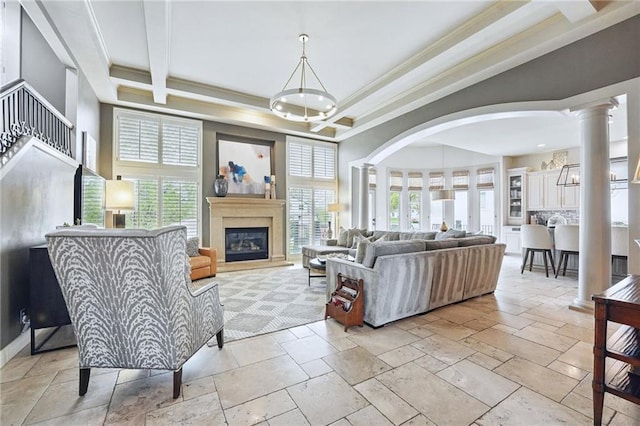 living area with crown molding, stone tile floors, arched walkways, and a healthy amount of sunlight