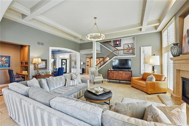 living room featuring visible vents, a towering ceiling, arched walkways, beam ceiling, and stairway