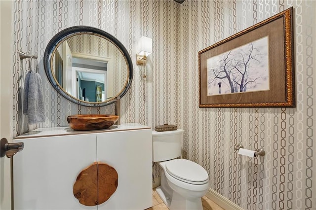 half bathroom with vanity, toilet, and wallpapered walls