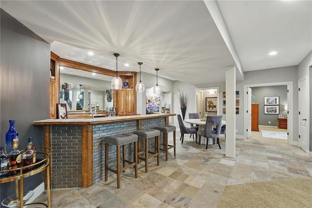 bar featuring a bar, pendant lighting, baseboards, and recessed lighting