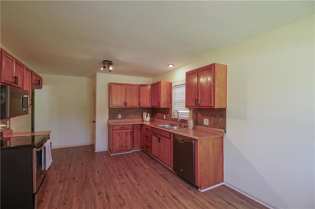 502 W Broadway St, Higginsville, MO 64037 - kitchen with appliances with stainless steel finishes, a sink, wood finished floors, decorative backsplash, and baseboards