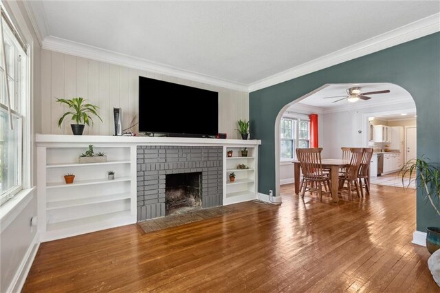 7227 Jefferson St, Kansas City, MO 64114 - living area featuring crown molding, arched walkways, wood-type flooring, ceiling fan, and a fireplace