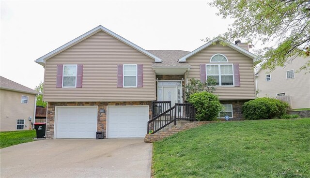 1215 Nottingham Dr, Warrensburg, MO 64093 - split foyer home with concrete driveway, an attached garage, stone siding, and a front lawn