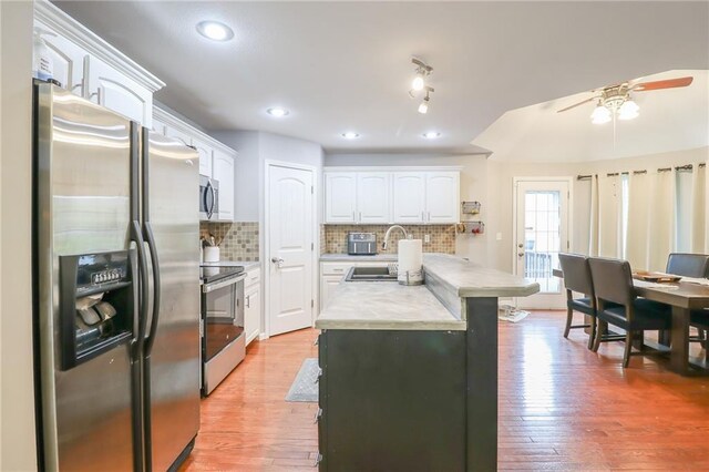 1215 Nottingham Dr, Warrensburg, MO 64093 - kitchen with appliances with stainless steel finishes, a sink, light countertops, white cabinetry, and backsplash