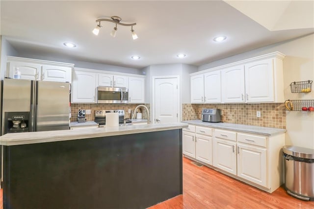 1215 Nottingham Dr, Warrensburg, MO 64093 - kitchen featuring appliances with stainless steel finishes, a sink, light wood finished floors, light countertops, and white cabinetry