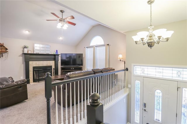 1215 Nottingham Dr, Warrensburg, MO 64093 - carpeted living area featuring vaulted ceiling, plenty of natural light, ceiling fan with notable chandelier, and a tile fireplace