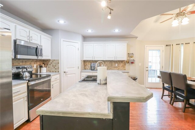 1215 Nottingham Dr, Warrensburg, MO 64093 - kitchen featuring ceiling fan, light countertops, white cabinets, stainless steel appliances, and an island with sink