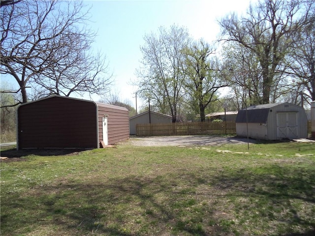 view of yard featuring an outdoor structure, fence, and a storage unit
