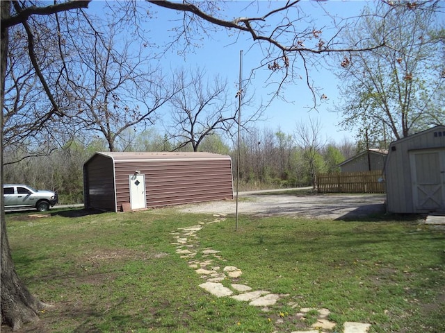 view of yard featuring fence, a storage unit, and an outdoor structure