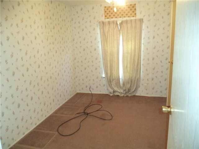unfurnished room featuring wallpapered walls and carpet
