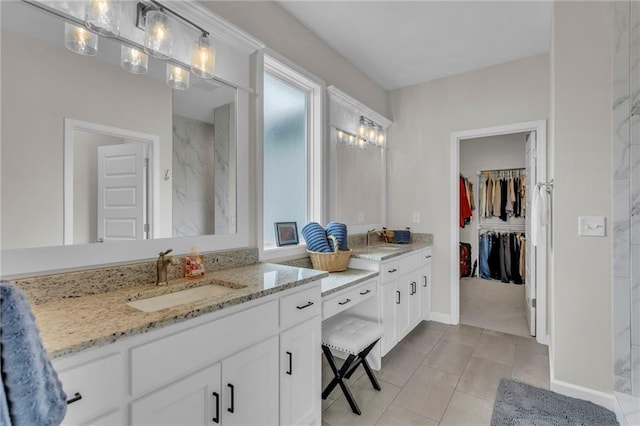 full bathroom featuring vanity, tile patterned flooring, baseboards, and a walk in closet