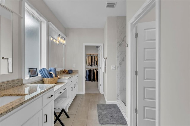 bathroom featuring a walk in closet, visible vents, tile patterned flooring, vanity, and a marble finish shower