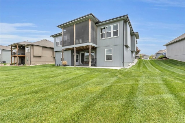 back of house featuring a lawn, a residential view, a patio area, and a sunroom