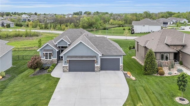view of front of house featuring an attached garage, a front yard, driveway, and stone siding
