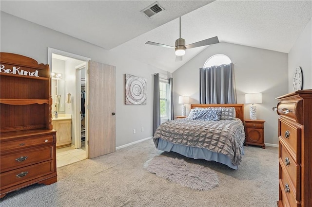 bedroom featuring light colored carpet, vaulted ceiling, baseboards, ceiling fan, and ensuite bathroom