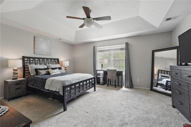 bedroom featuring a tray ceiling, light carpet, ceiling fan, a textured ceiling, and baseboards
