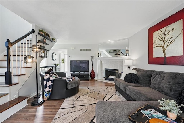 living room featuring wood finished floors, stairs, and a tiled fireplace