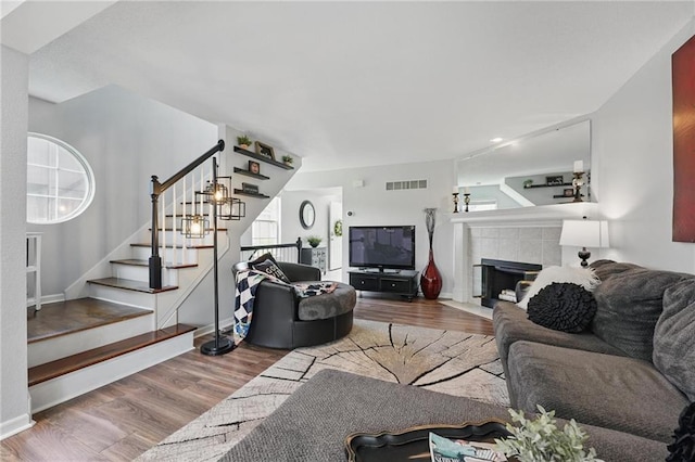 living area with wood finished floors, stairway, plenty of natural light, and baseboards