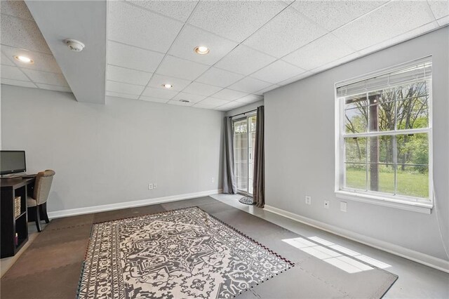 unfurnished office featuring a paneled ceiling, plenty of natural light, baseboards, and recessed lighting