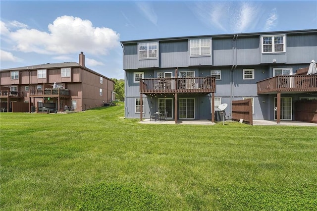 back of house with a lawn, a wooden deck, and a patio