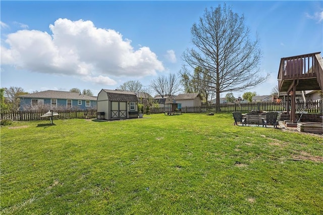 view of yard featuring a fenced backyard, an outdoor fire pit, a shed, and an outbuilding