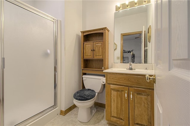 bathroom featuring tile patterned flooring, a shower stall, toilet, vanity, and baseboards