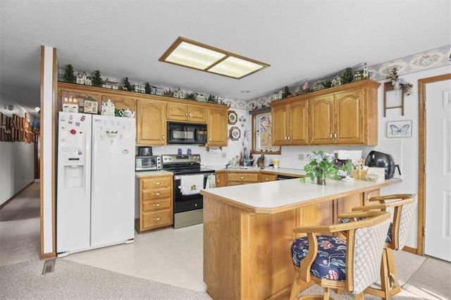 kitchen featuring stainless steel electric stove, a kitchen breakfast bar, white refrigerator with ice dispenser, black microwave, and light countertops