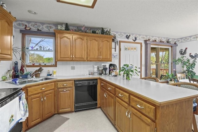 kitchen featuring brown cabinets, light countertops, a peninsula, black dishwasher, and a textured ceiling
