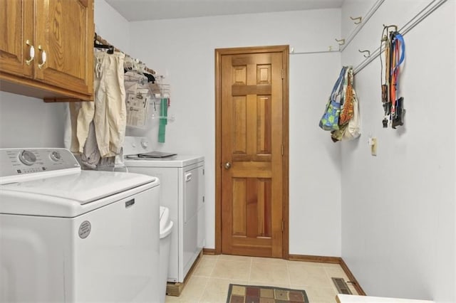 clothes washing area with separate washer and dryer, baseboards, light tile patterned flooring, and cabinet space