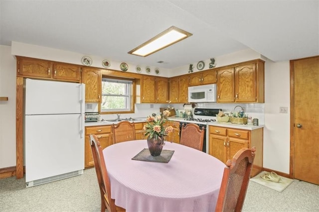 kitchen featuring light carpet, light countertops, white appliances, and brown cabinets