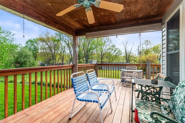 deck featuring a ceiling fan and a lawn