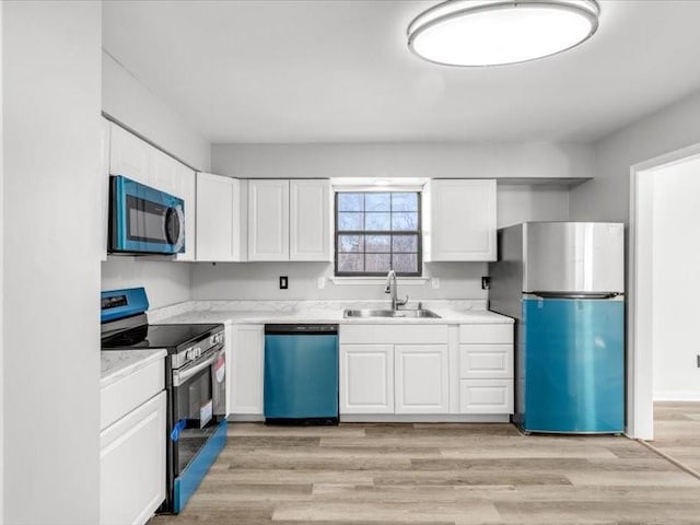 5836 Blue Ridge Blvd, Raytown, MO 64133 - kitchen featuring appliances with stainless steel finishes, a sink, white cabinetry, and light wood-style floors